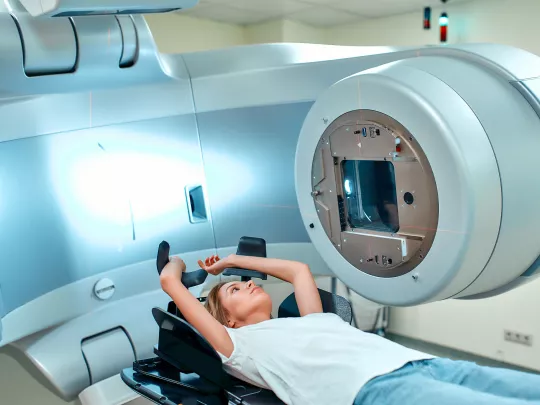 一名妇女躺在放射治疗机前的医疗沙发上