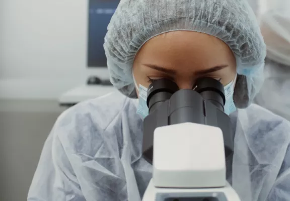 实验室里的一位女性通过显微镜进行观察。