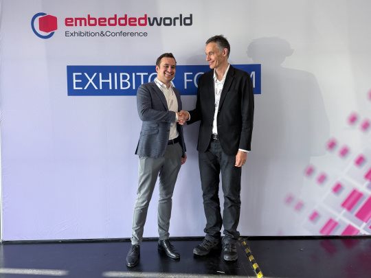 两位董事总经理在Embedded World展览墙前握手